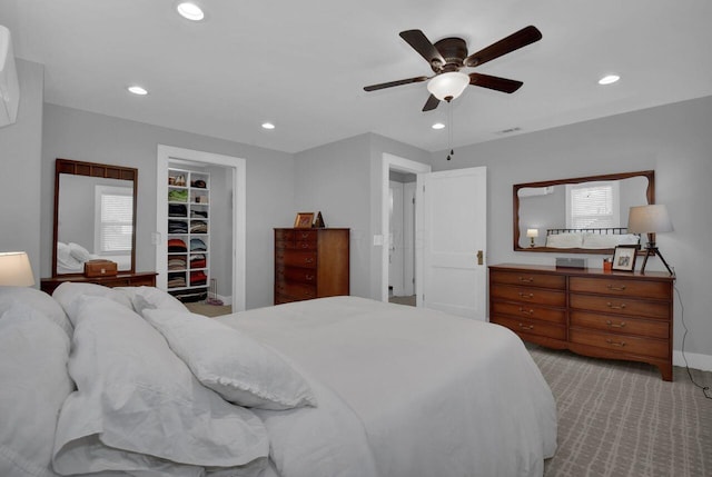 bedroom featuring ceiling fan, light colored carpet, a walk in closet, and a closet