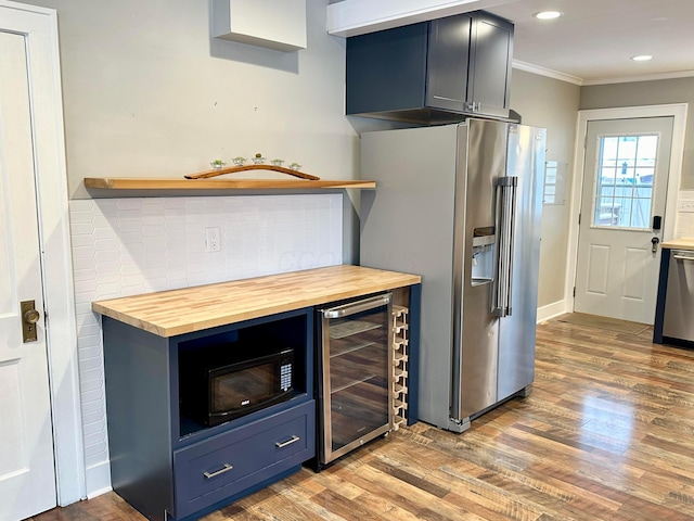 kitchen with wooden counters, ornamental molding, stainless steel appliances, blue cabinets, and beverage cooler