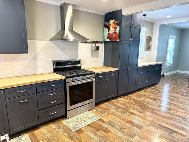 kitchen featuring butcher block counters, wall chimney exhaust hood, stainless steel gas range oven, pendant lighting, and ornamental molding