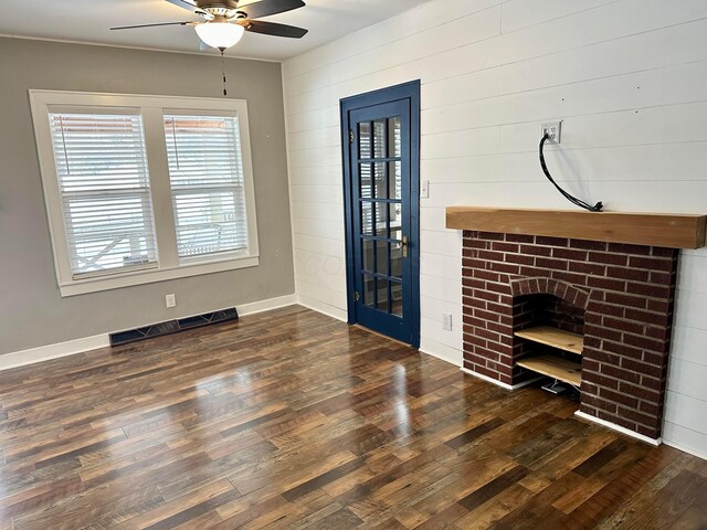 unfurnished living room featuring ceiling fan, wood walls, and dark hardwood / wood-style flooring