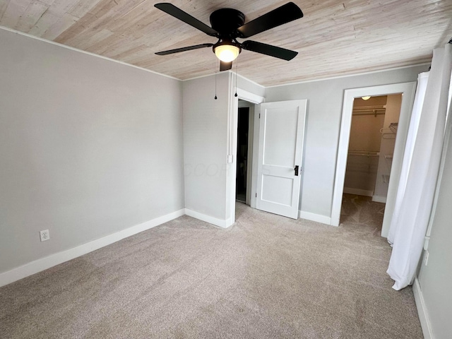 unfurnished bedroom featuring carpet flooring, a walk in closet, wood ceiling, ceiling fan, and a closet