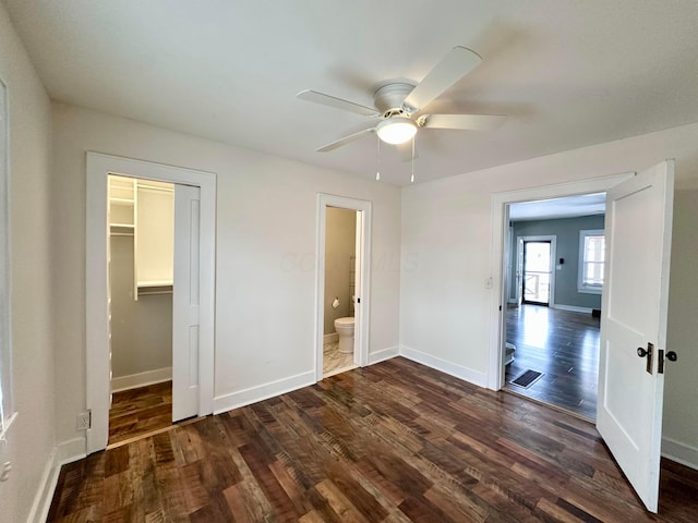 unfurnished bedroom featuring dark hardwood / wood-style flooring, ceiling fan, a closet, and a walk in closet