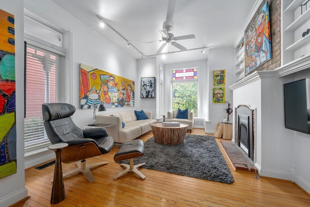 living room with light wood-type flooring, track lighting, and ceiling fan