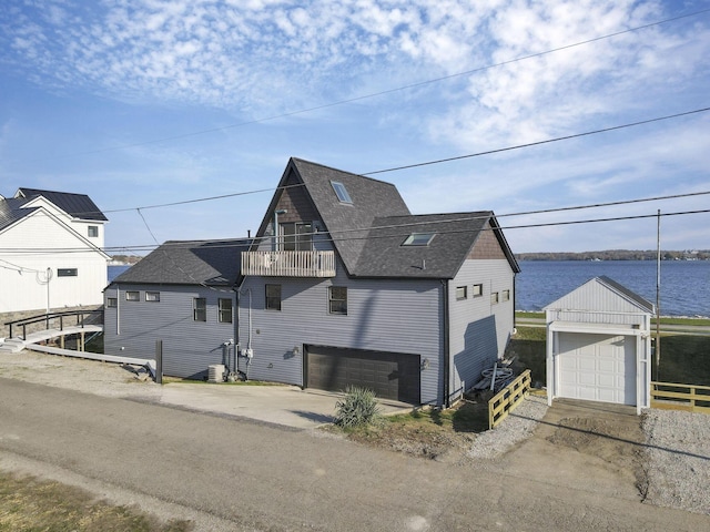 view of front of property with a balcony, a water view, central AC unit, and a garage