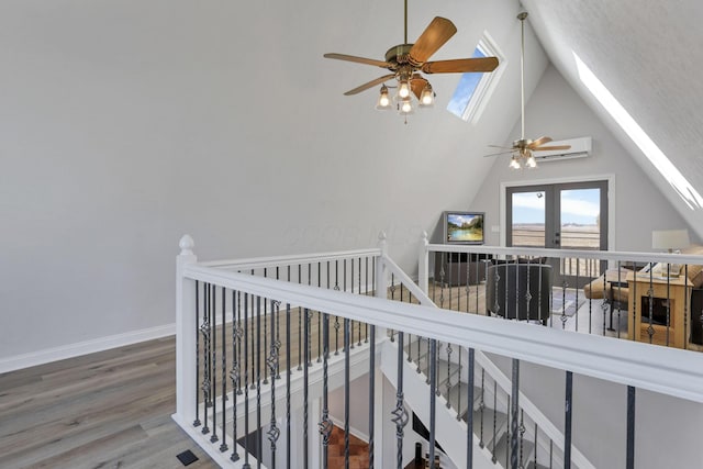 hall featuring hardwood / wood-style flooring, lofted ceiling with skylight, and french doors