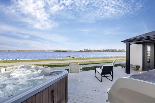 deck with a water view and a hot tub