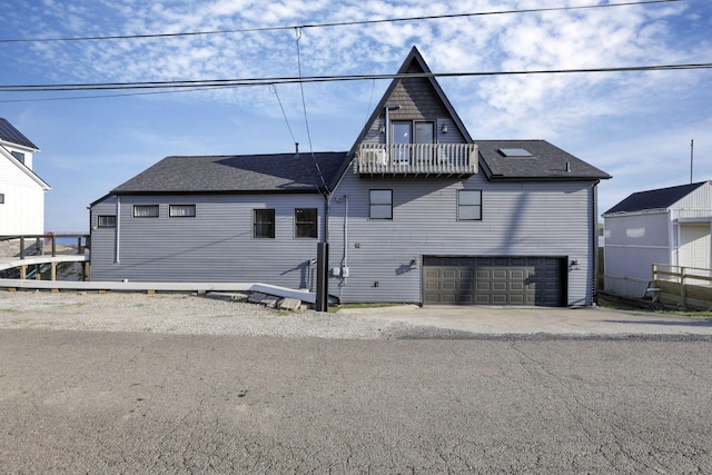 rear view of house featuring a balcony and a garage