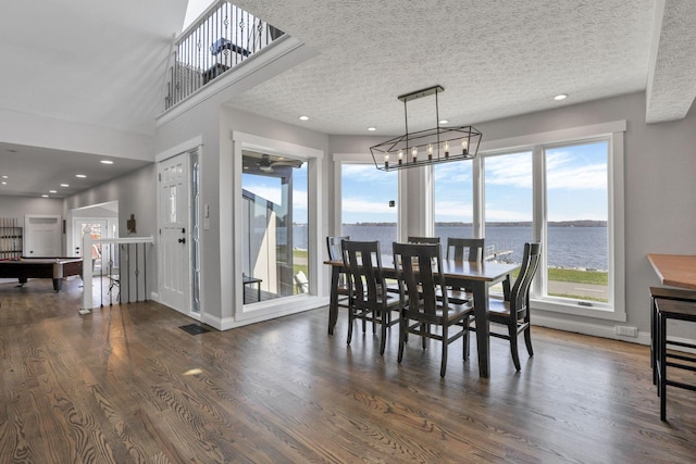 dining space with a water view, dark hardwood / wood-style floors, and a healthy amount of sunlight