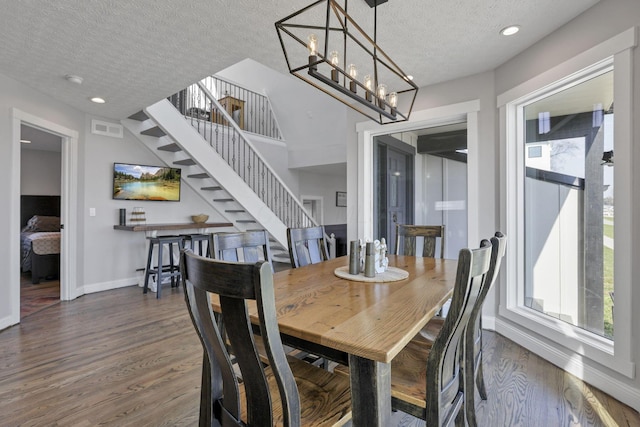 dining area with dark hardwood / wood-style floors, a textured ceiling, and an inviting chandelier