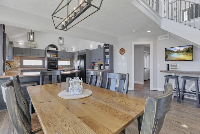 dining area with lofted ceiling, a textured ceiling, and dark wood-type flooring