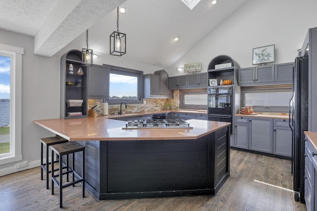 kitchen featuring gray cabinetry, dark hardwood / wood-style flooring, kitchen peninsula, a breakfast bar area, and black appliances