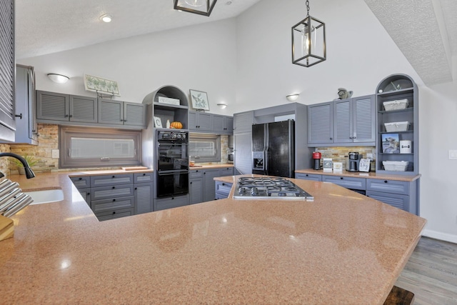 kitchen with pendant lighting, sink, a textured ceiling, and black appliances