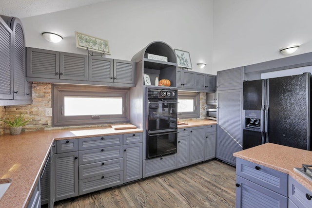 kitchen with black appliances, decorative backsplash, a textured ceiling, and hardwood / wood-style flooring