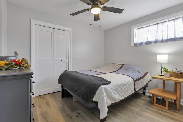 bedroom featuring a textured ceiling, light wood-type flooring, a closet, and ceiling fan