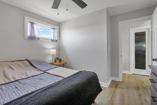 bedroom with ceiling fan, a textured ceiling, and light hardwood / wood-style flooring