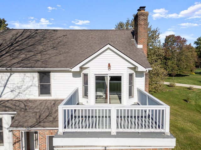 back of property featuring a wooden deck and a lawn