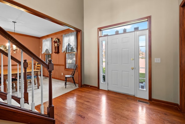 entrance foyer featuring wood-type flooring, crown molding, and an inviting chandelier