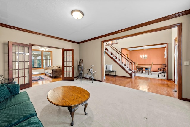 living room with french doors, light wood-type flooring, a textured ceiling, ornamental molding, and a notable chandelier