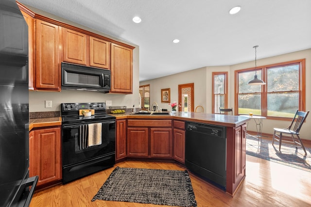 kitchen featuring black appliances, light hardwood / wood-style floors, and kitchen peninsula