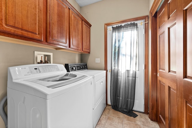 laundry room with washer and dryer, light tile patterned flooring, and cabinets