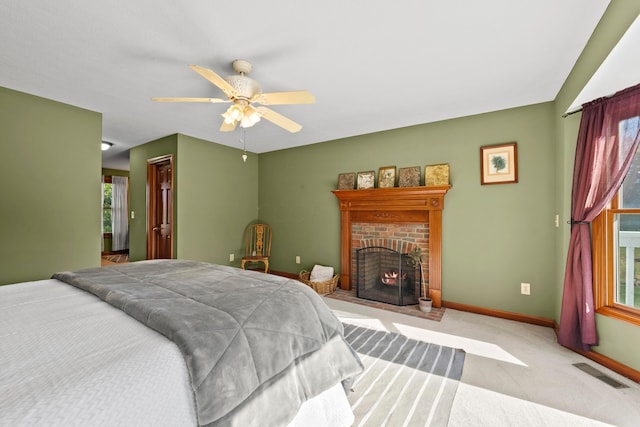 carpeted bedroom featuring a brick fireplace and ceiling fan