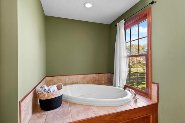 bathroom with a relaxing tiled tub and a textured ceiling