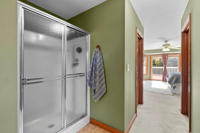 bathroom with ceiling fan, an enclosed shower, and a textured ceiling