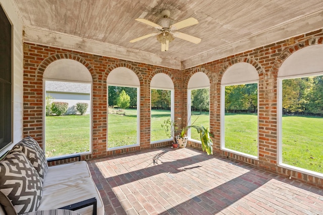 unfurnished sunroom with ceiling fan, plenty of natural light, and wooden ceiling