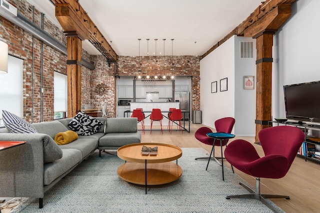 living room featuring beam ceiling, brick wall, and wood-type flooring