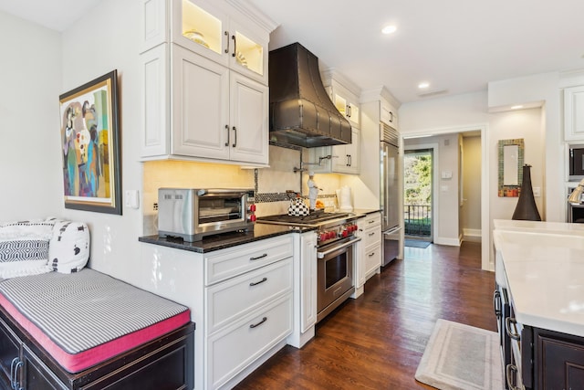 kitchen with white cabinets, extractor fan, built in appliances, backsplash, and dark hardwood / wood-style floors