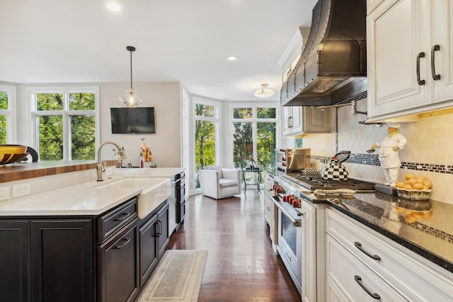 kitchen featuring extractor fan, pendant lighting, stainless steel stove, white cabinets, and sink