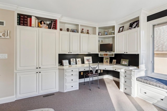 office featuring light colored carpet, ornamental molding, and built in desk