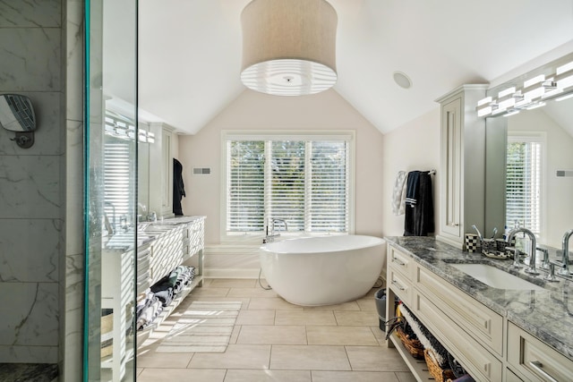 bathroom featuring lofted ceiling, vanity, and a bath