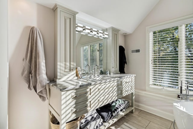 bathroom with sink, a bath, lofted ceiling, and a healthy amount of sunlight