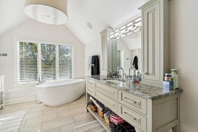 bathroom with a washtub, tile patterned flooring, vanity, and vaulted ceiling