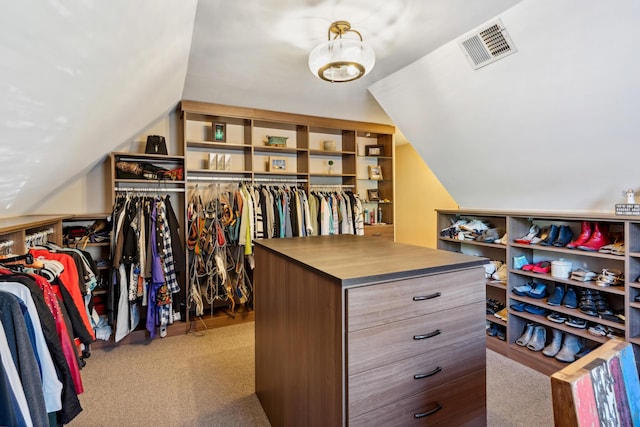 walk in closet with lofted ceiling and light colored carpet