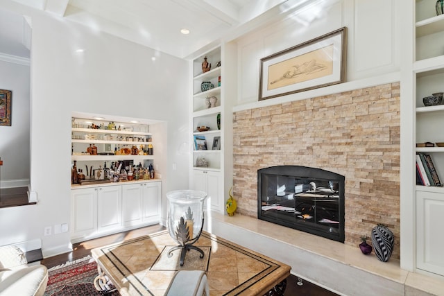 living room with hardwood / wood-style flooring, bar area, built in features, and a fireplace