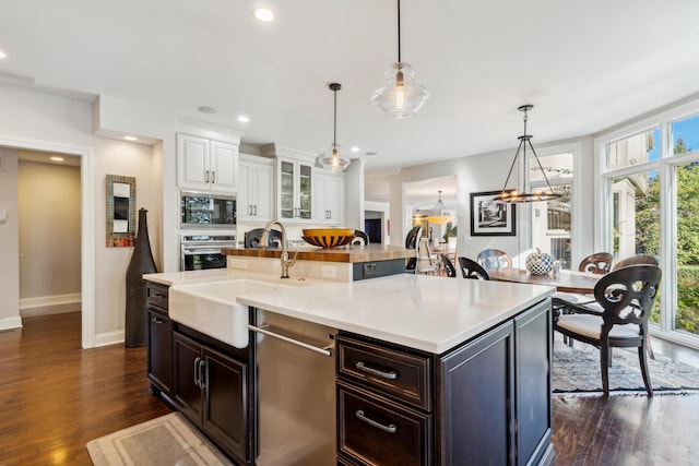 kitchen with pendant lighting, white cabinetry, black microwave, sink, and wall oven