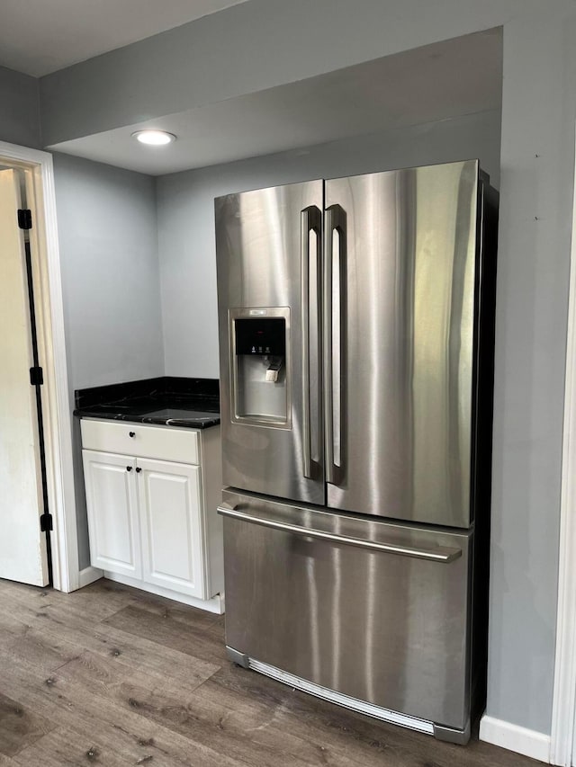 kitchen with stainless steel fridge with ice dispenser, white cabinets, and wood-type flooring