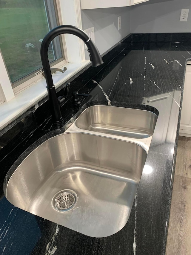 room details featuring white cabinets, dark stone counters, and sink