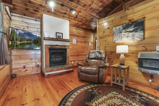 sitting room with wood ceiling, heating unit, vaulted ceiling, wooden walls, and wood-type flooring