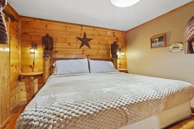 bedroom featuring hardwood / wood-style flooring, ornamental molding, and wooden walls