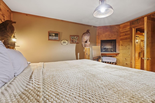 bedroom with a tile fireplace, ornamental molding, and wooden walls