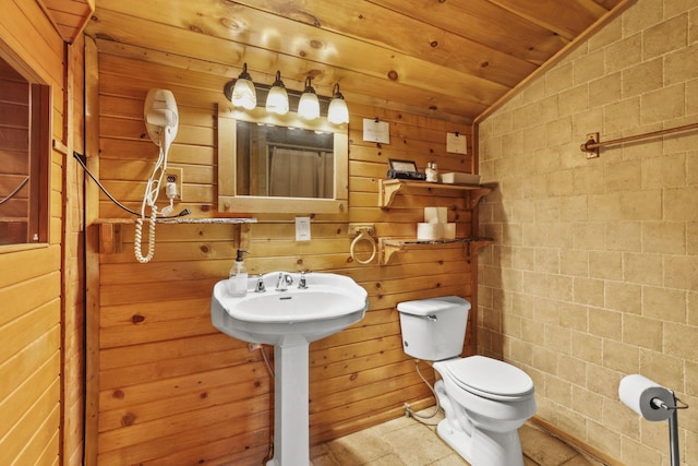 bathroom featuring wooden ceiling, lofted ceiling, toilet, wooden walls, and tile walls