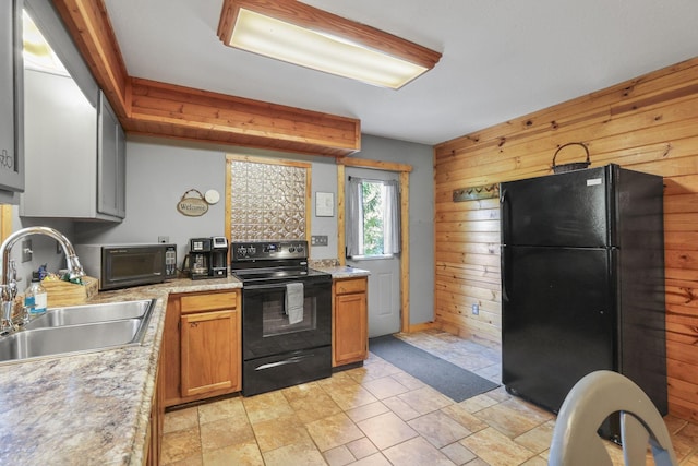 kitchen with black appliances, wood walls, and sink