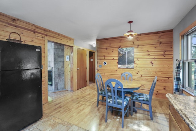 dining room with light hardwood / wood-style floors, plenty of natural light, and wooden walls