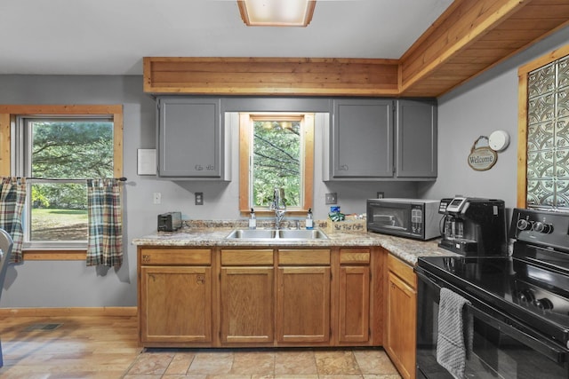 kitchen featuring a healthy amount of sunlight, sink, black appliances, and light wood-type flooring