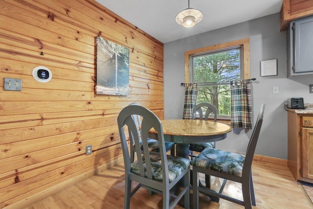 dining room with wood walls and light hardwood / wood-style flooring