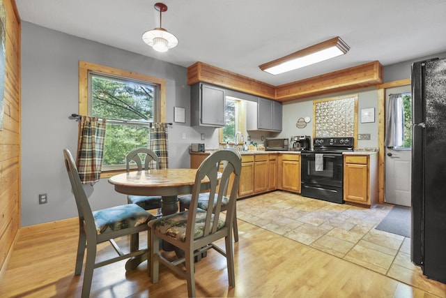 kitchen with black appliances, a healthy amount of sunlight, light hardwood / wood-style floors, and pendant lighting