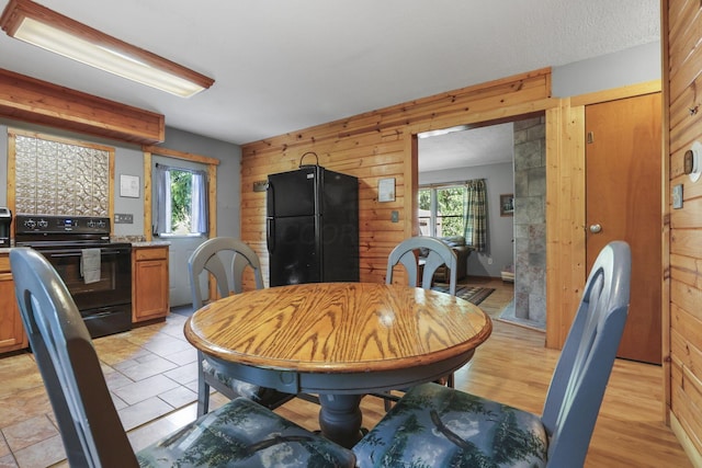 dining space with light hardwood / wood-style floors, a healthy amount of sunlight, and wood walls